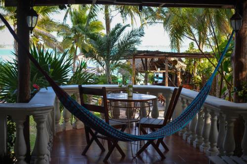 a hammock on a balcony with a table and chairs at Tortuga Bacalar in Bacalar