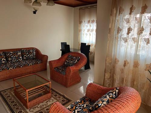 sala de estar con sillas de mimbre y mesa en Nicole Residence en Yaundé