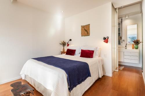 een witte slaapkamer met een groot bed met rode kussens bij Unhotel-Home Office Loft Vista para Lagoa in Rio de Janeiro