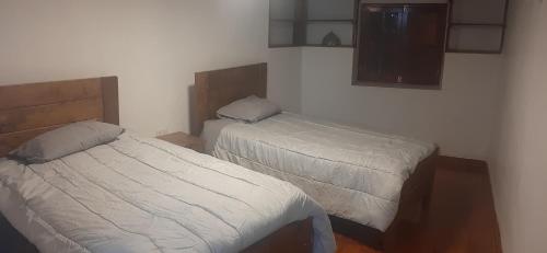 a bedroom with two beds and a tv on the wall at Taita wasi in Cajamarca