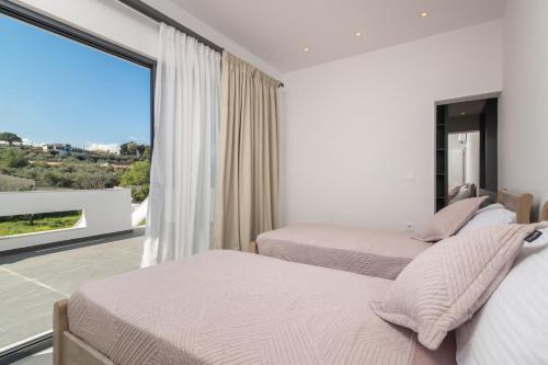 two beds in a bedroom with a large window at Mare Vento II in Zakynthos Town