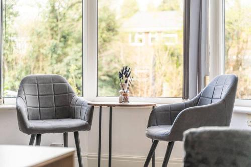 2 Stühle und ein Tisch vor einem Fenster in der Unterkunft Detached House with Free Parking, Fast Wifi, Smart TV and Garden by Yoko Property in Coventry