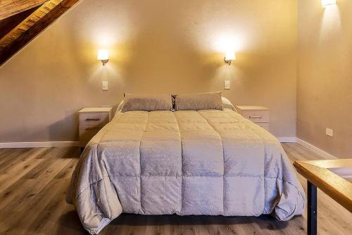 ein Schlafzimmer mit einem großen Bett mit zwei Nachttischen in der Unterkunft Happy Host - Domo Paisajismo in Villa La Angostura