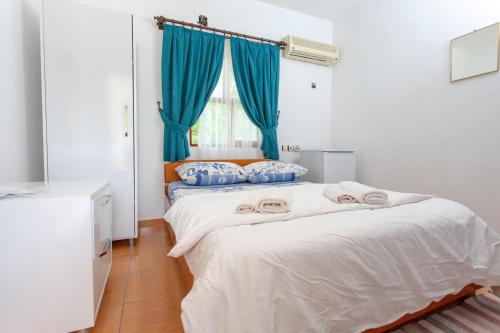 two beds in a room with blue curtains at Baris Pension & Bungalows in Cıralı