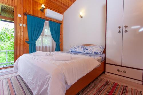 a bedroom with a bed with blue curtains and a window at Baris Pension & Bungalows in Cıralı