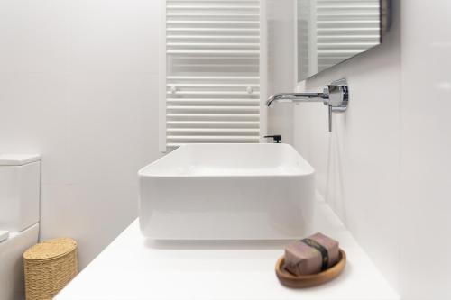 a white bathroom with a sink and a faucet at Grandvalira Hogar Acogedor con Terraza y Parking I AndBnB in El Tarter