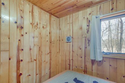 um quarto de madeira com uma cama e uma janela em Wooded Park Rapids Cabin Lake Access, Boat Slip! em Arago