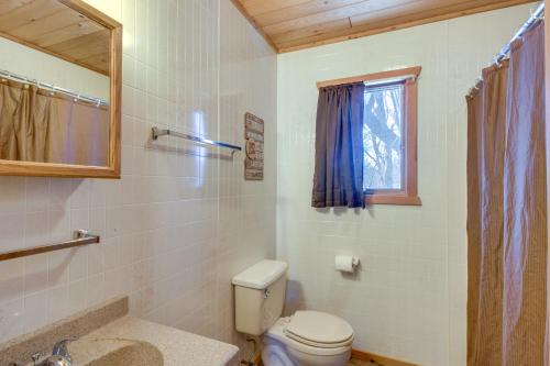 La salle de bains est pourvue de toilettes, d'un lavabo et d'une fenêtre. dans l'établissement Serene Park Rapids Cabin Fire Pit, Lake Access!, à Arago