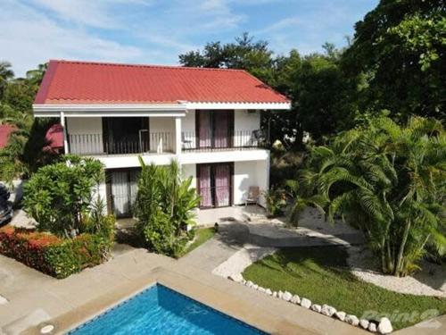 una casa con techo rojo y piscina en 2-BD Unit with Pool 2 Blocks from Beach en Coco