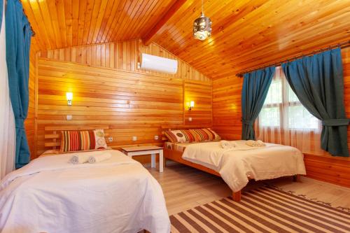 a bedroom with two beds in a wooden cabin at Baris Pension & Bungalows in Cıralı