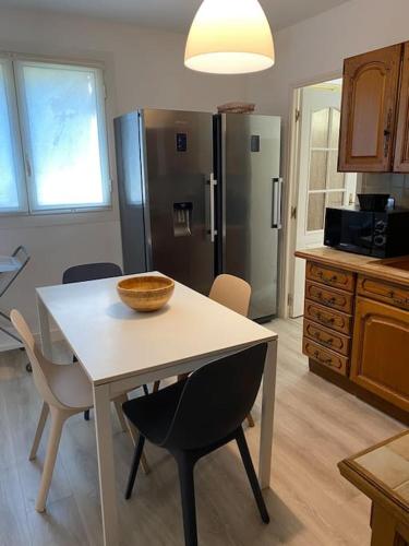 une cuisine avec une table avec des chaises et un réfrigérateur dans l'établissement Appartement Bastia entièrement climatisé vue mer, à Bastia