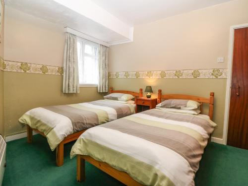 Cette chambre comprend 2 lits et une fenêtre. dans l'établissement First Floor Apartment, à Porthmadog