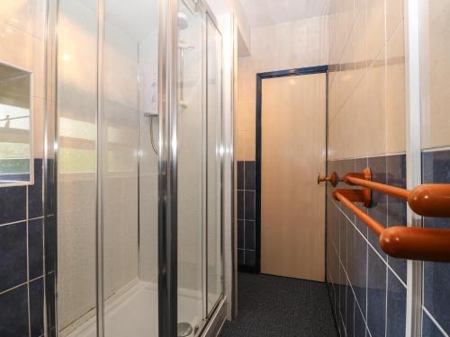 y baño con ducha y puerta de cristal. en First Floor Apartment en Porthmadog
