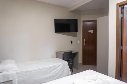 a room with two beds and a desk and a television at Amazon Green Hotel in Lucas do Rio Verde