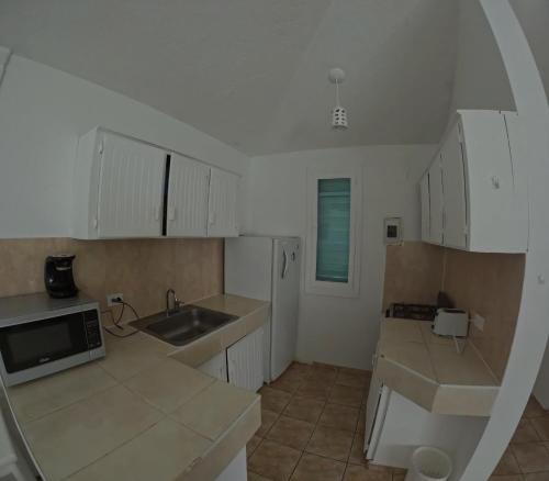 a kitchen with white cabinets and a sink and a refrigerator at Hotel El Legendario in Sosúa