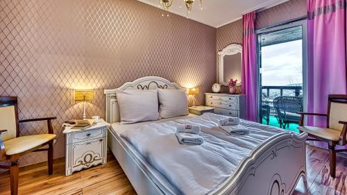 1 dormitorio con cama blanca y ventana en Apartament nad Elementsem 29 - 5D Apartamenty, en Świeradów-Zdrój