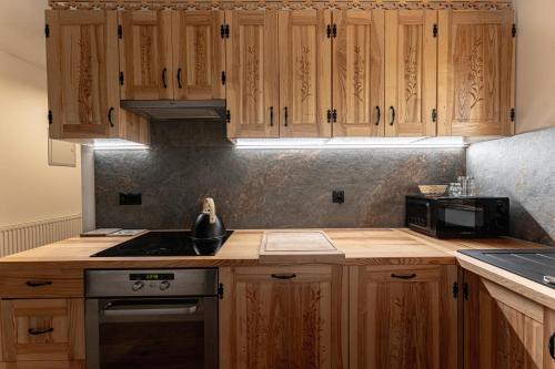 a kitchen with wooden cabinets and a stove top oven at Chata Nad Jeziorem Czorsztyńskim -Jaquzzi zewnętrzne in Maniowy