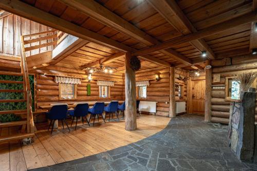 a dining room in a log cabin with blue chairs at Chata Nad Jeziorem in Maniowy