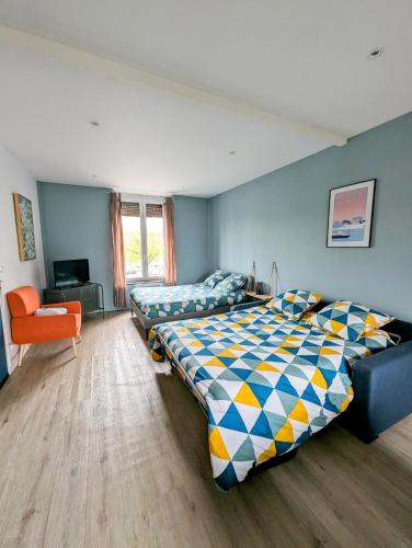 - une chambre avec deux lits et une chaise orange dans l'établissement Oslo - Appartement Spacieux et Cosy, à Charleville-Mézières