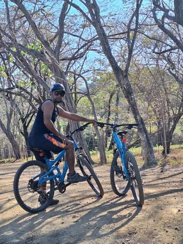 a man riding a blue bike on a dirt road at Casa Jungla Playa Avellanas in Río Sequito