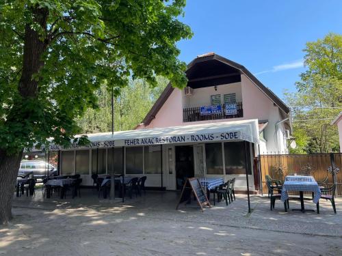 a restaurant with tables and chairs in front of a building at Feher Akac Guest House in Palić