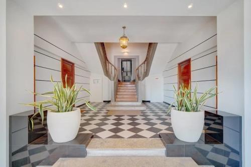 un couloir avec deux plantes en pot sur un sol en damier dans l'établissement Villa Luna Nova, à Cannes