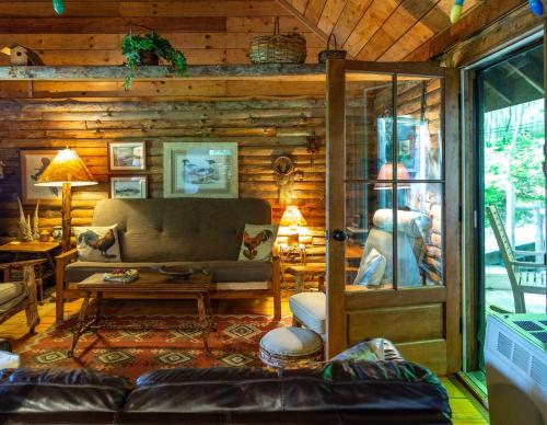 a living room with a couch in a log cabin at Cozy Cottage on Pond in Great Valley