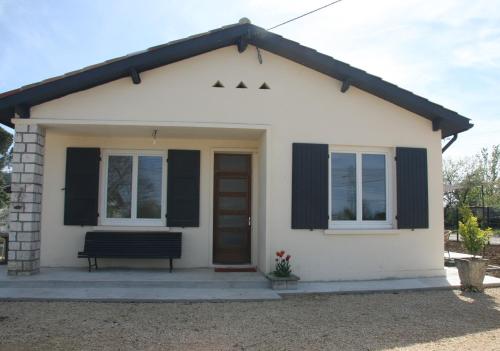 une petite maison blanche avec un banc devant dans l'établissement GITE chez mamie - 7 personnes A SAINTE LIVRADE SUR LOT, à Sainte-Livrade-sur-Lot