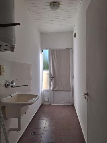a white bathroom with a sink and a window at Departamentos MR in Villa Elisa