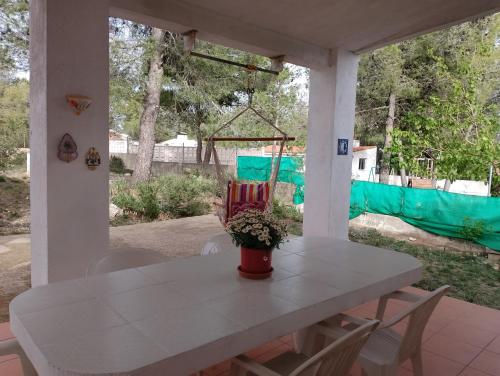 une table blanche avec une plante en pot sur une terrasse couverte dans l'établissement Casa Refugio Entre Pinos y Romeros, à Mogente