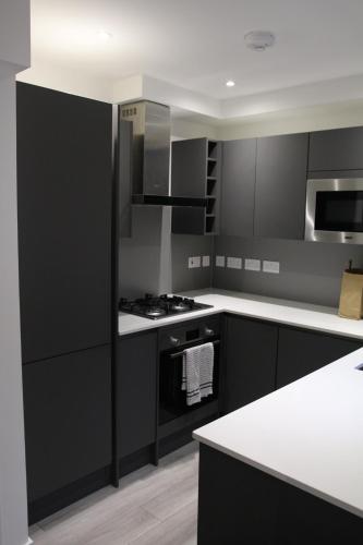 a kitchen with black cabinets and white counter tops at Brand new Greenwich house-Heart of London-Great connections to Central London in London