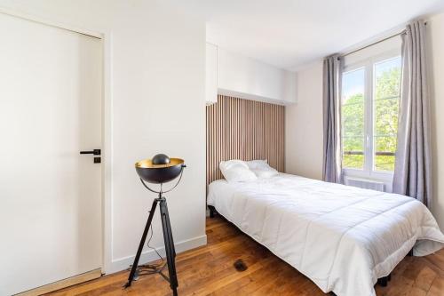 une chambre blanche avec un lit et une fenêtre dans l'établissement Bail mobilité - Appartement pour voyages d'affaires et d'études, à Paris