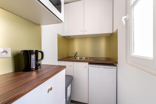 une petite cuisine avec des armoires blanches et un évier dans l'établissement Bail mobilité - Appartement pour voyages d'affaires et d'études, à Paris