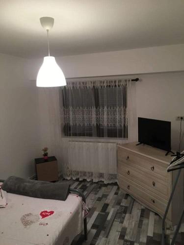 a bedroom with a bed and a dresser and a television at apartament Sara in Mangalia