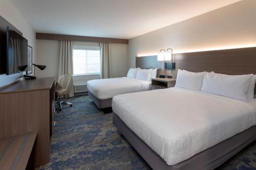 a hotel room with two beds and a television at GrandStay Hotel & Suites Johnston-Des Moines, IA in Johnston