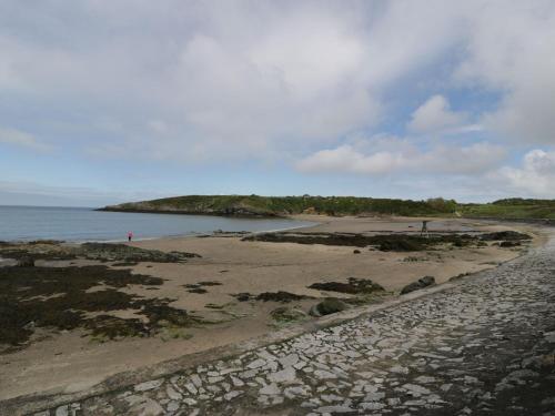 a beach with rocks and the ocean on a cloudy day at Ty Bara in Cemaes Bay