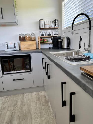 a kitchen with white cabinets and a sink at Hills Vista Lodge in Matamata