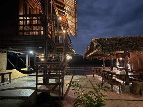 un patio con mesas y sillas de madera y un edificio en HOTEL RM en Nuquí