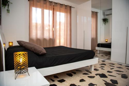 a bedroom with a bed with black sheets and a lamp at Roma amoR Vitinia in Vitinia