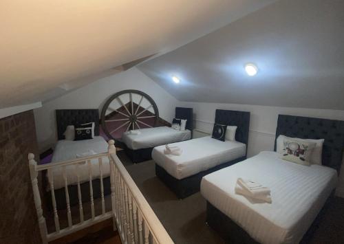 a attic room with three beds and a staircase at Button Street by UStay Aparthotels in Liverpool