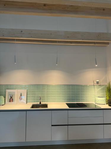 a kitchen with white cabinets and a sink at Sievershof Poolloft in Wietzendorf