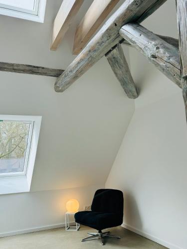 a black chair in a room with wooden beams at Sievershof Poolloft in Wietzendorf