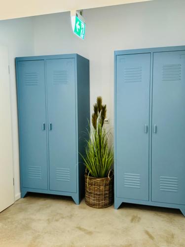 two blue lockers in a room with a potted plant at Sievershof Poolloft in Wietzendorf