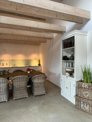 a dining room with a table and wicker chairs at Sievershof Poolloft in Wietzendorf