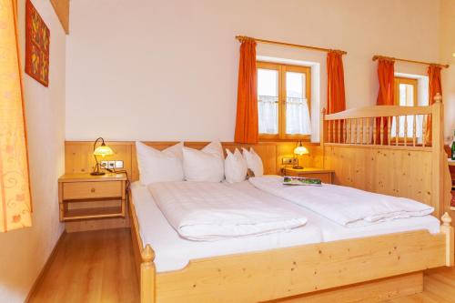 a bedroom with a large wooden bed with white sheets at Demelhof in Reit im Winkl