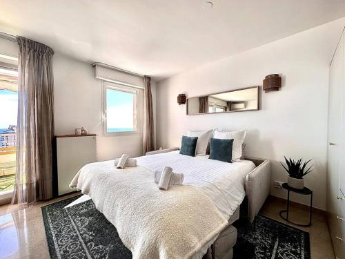 um quarto com uma grande cama branca e um espelho em Monte Carlo Vista - Vue Mer - Terrasse em Beausoleil