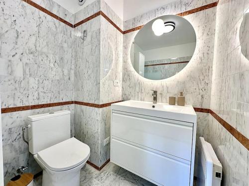 uma casa de banho com um WC, um lavatório e um espelho. em Monte Carlo Vista - Vue Mer - Terrasse em Beausoleil