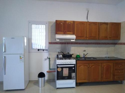 a kitchen with a white stove and a refrigerator at Apartamentos Anahí in Villa Parque Siquiman