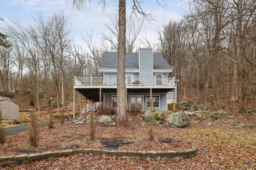 a blue house with a balcony in the woods at Large home in community w/pools&skiing in Bushkill