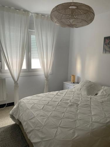 een slaapkamer met een groot bed en een kroonluchter bij Apartamento a pie de playa en Miño in Miño